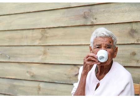 fisioterapia geriátrica Senhora bebendo café, sentada do lado de fora da casa